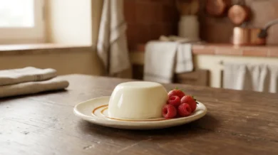 Klasyczna panna cotta - kremowa biała kopułka na talerzyku, obok karmel i świeże owoce leśne, w rustykalnej włoskiej kuchni